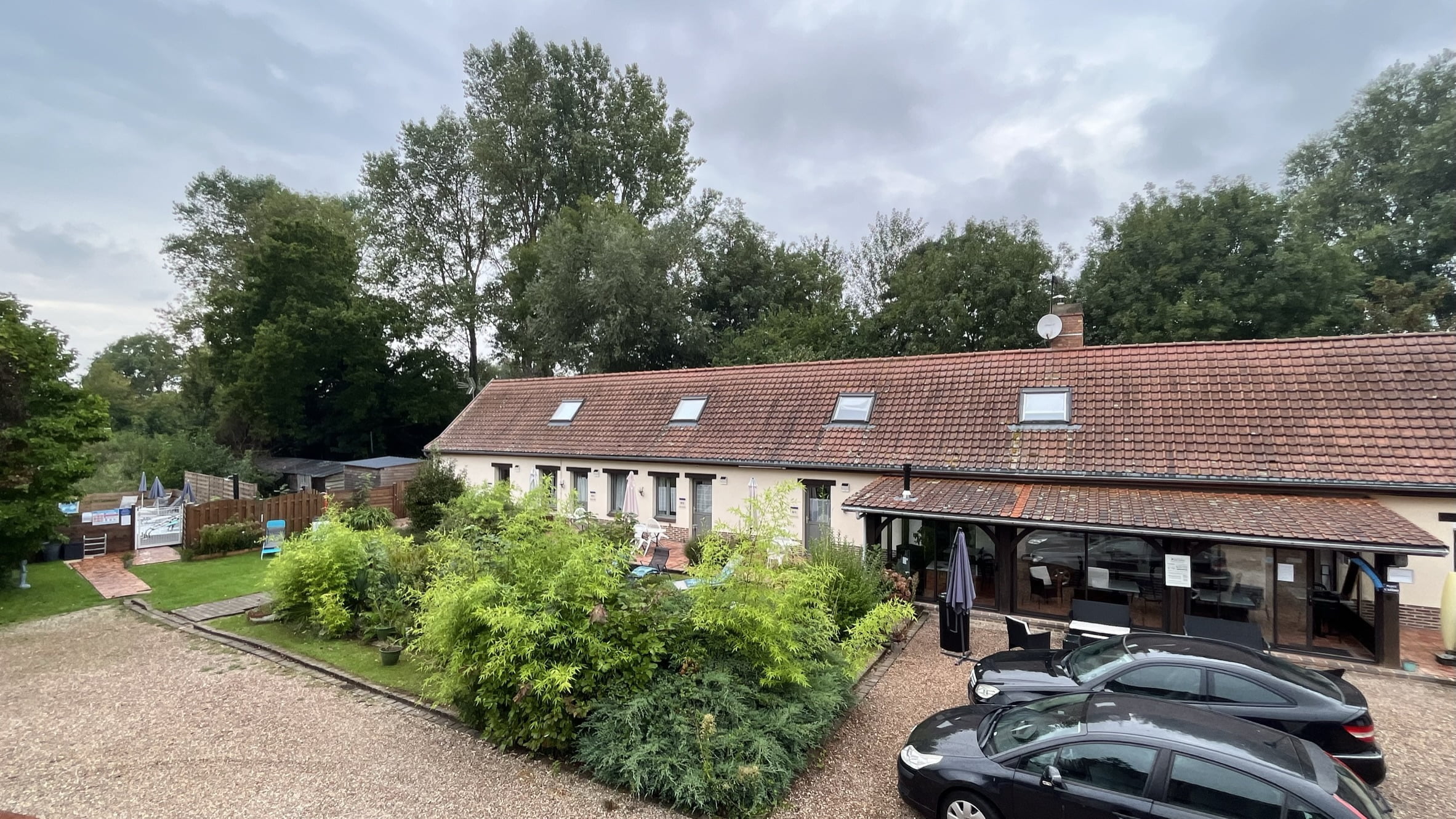 Bâtiment principal avec la véranda en face et la piscine sur la gauche.